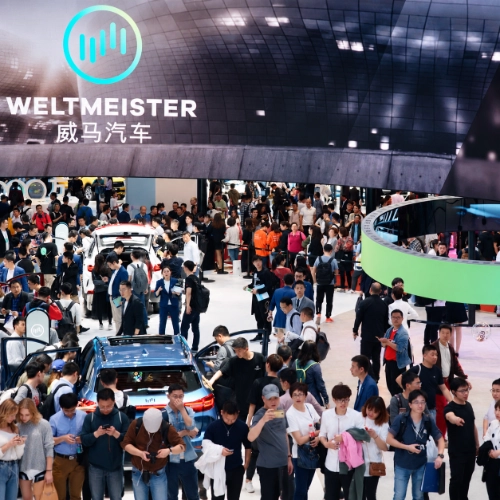 Crowded automotive event booth showcasing interactive multi-platform 3D digital experiences.